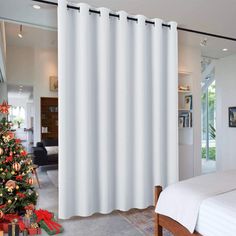 a bedroom with a christmas tree in the corner and a white curtain hanging from the window