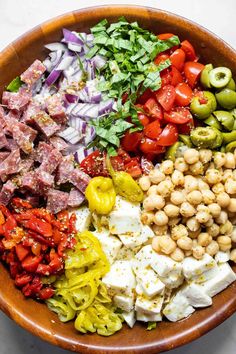 a wooden bowl filled with lots of different types of food on top of a table