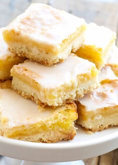 a white plate topped with lemon bars covered in frosting