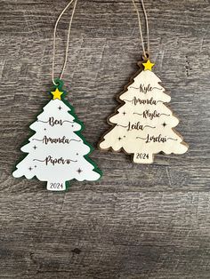 two wooden christmas trees hanging from strings on a wood table with the names of each tree