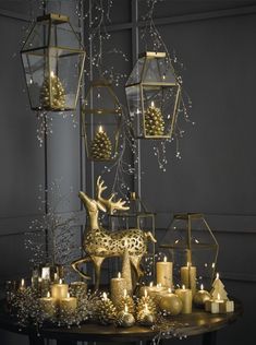 a table topped with lots of candles and christmas decorations next to a lantern holder filled with ornaments