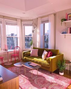 a living room filled with furniture and lots of windows next to a wooden floor covered in pink rugs