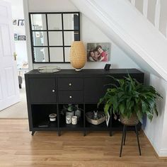 a room with a plant and some pictures on the wall next to a dresser in it