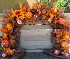 a wooden bench topped with lots of fall leaves and wreaths on top of it