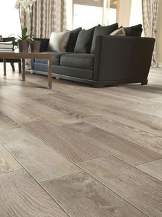 a living room filled with furniture and a wooden floor covered in hard wood planks