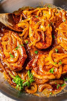 some food is being cooked in a pan with a wooden spoon on the side and garnished with parsley