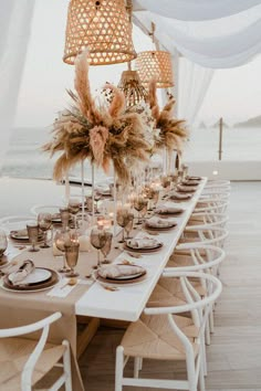 a table set up with place settings and flowers on it for an outdoor dinner party