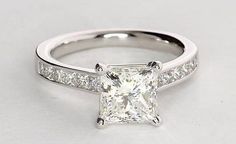 a princess cut diamond engagement ring with channel set diamonds on the band and side stones