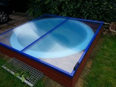 a large blue swimming pool sitting on top of a grass covered ground next to a fence