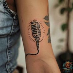 a woman's arm with a microphone tattoo on the left side of her arm