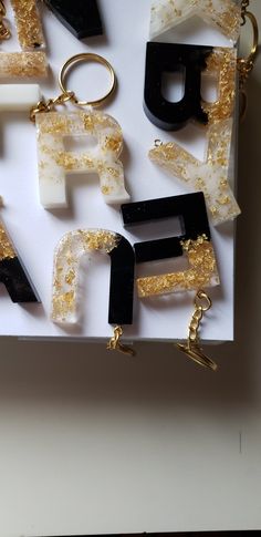 Show off your personality with this handcrafted initial keychain, made with black, clear and gold epoxy resin and gold foil flakes. Each keychain is unique and measures approx. 1.5” tall - perfect for keeping your keys stylishly organized. It comes with gold hardware, but other color options are available upon request. NOTE: Each keychain is made to order, is unique, and will have slight variations from the product images. Because the product is made with epoxy resin, there may be small air bubb Epoxy Resin Keychains Glamhues, Resin Initial Keychain, Keychain Black, Letter Keychain, Initial Keychain, Diy Resin Projects, Handmade Keychain, Unique Keychains, Resin Projects