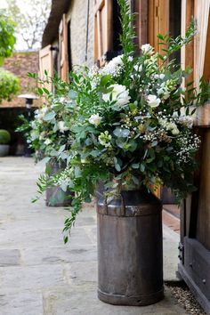 a metal bucket with flowers in it sitting on the side of a building