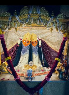 an idol is sitting in the middle of a stage with flowers on it and decorations around it