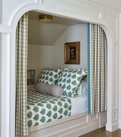 a bed sitting in the corner of a room under a window with curtains on it