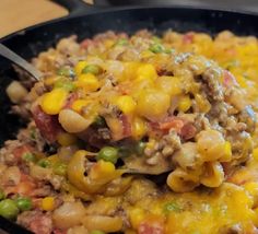 a skillet filled with macaroni and cheese on top of a wooden table