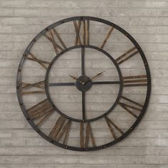 a large metal clock mounted to the side of a brick wall with roman numerals