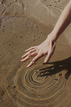 a person reaching for something in the sand with their hand on top of it,