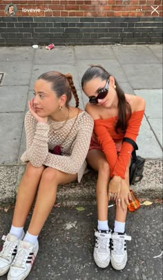 two young women sitting on the ground next to each other