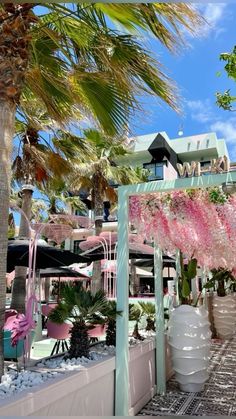 there are many potted plants in front of the building with pink flowers on it