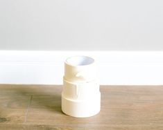 a white cup sitting on top of a wooden floor