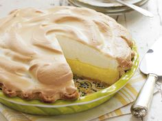 a lemon meringue pie on a plate with a slice cut out and ready to be eaten