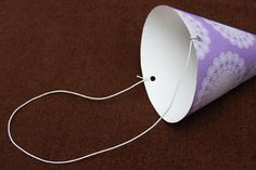 a purple and white paper cone with a string attached to it on a brown surface