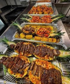 several trays filled with different types of food on top of a metal counter in a kitchen