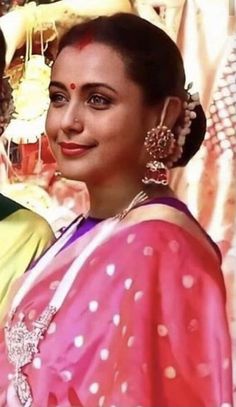 two women in sari are posing for the camera with their heads turned to look like they