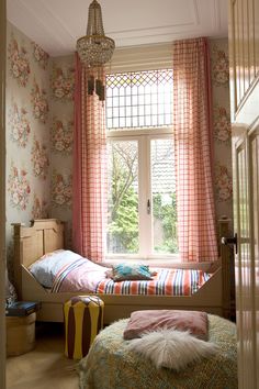 a bedroom with floral wallpaper and pink curtains