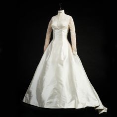 a white wedding dress with long sleeves and lace on the top is displayed in front of a black background