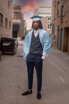 a man in a graduation gown standing on the street with his hands in his pockets