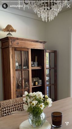 a vase with white flowers sitting on top of a table next to a book shelf