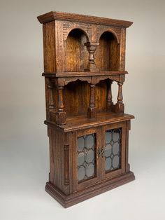 an old wooden cabinet with glass doors on the front and side shelves in the middle