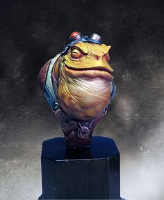 a statue of a frog wearing a helmet on top of a wooden block in front of a dark background