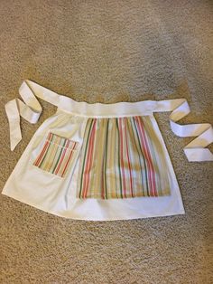 an apron made out of white fabric and ties on the floor with one piece cut off