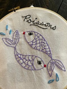 a close up of a embroidery on a piece of cloth with an embroidered fish and words