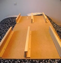 an unfinished bed frame sitting on top of a black and white bedspread