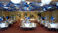 a room filled with tables and chairs covered in blue and white balloons, streamers and decorations