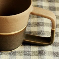 a brown coffee cup sitting on top of a checkered table cloth