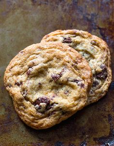 two chocolate chip cookies sitting on top of a baking sheet