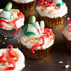 cupcakes decorated with white frosting and red, green, and gold decorations