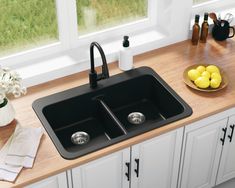 a kitchen sink sitting on top of a counter next to a bowl of lemons