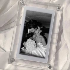 a bride and groom kissing in their wedding photo frame with white fabric draped around them