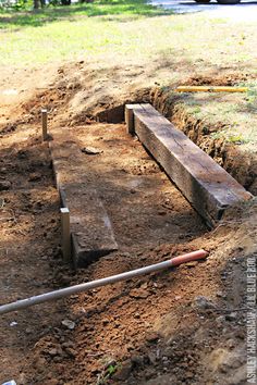 a wooden bench sitting in the middle of a dirt field next to a tree trunk