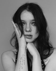 black and white photograph of a woman with her hands on her face, looking at the camera