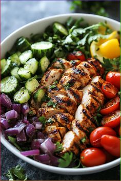 a salad with chicken, cucumbers, tomatoes and red onions in a white bowl