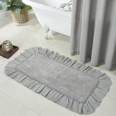 a white bath tub sitting next to a gray rug on top of a bathroom floor