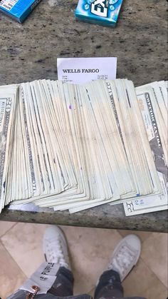 a pile of money sitting on top of a counter next to a pair of shoes