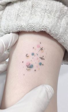 a woman's thigh with small stars and planets on her left side ribcage