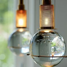 some lights that are hanging from the ceiling in front of a window and one has a reflection on it